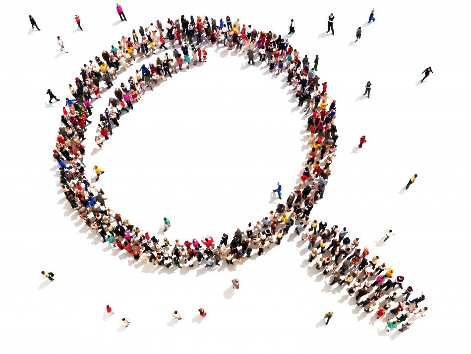 Group of people that have created a large scale image of a magnifying glass